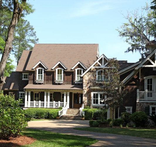 brown two-story home with white porch railing