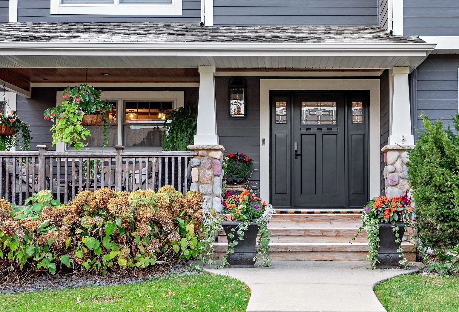 front porch with black door and hanging plants