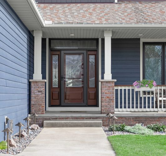 front porch of dark blue home with brown door