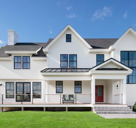 facade of white home with black windows and red door
