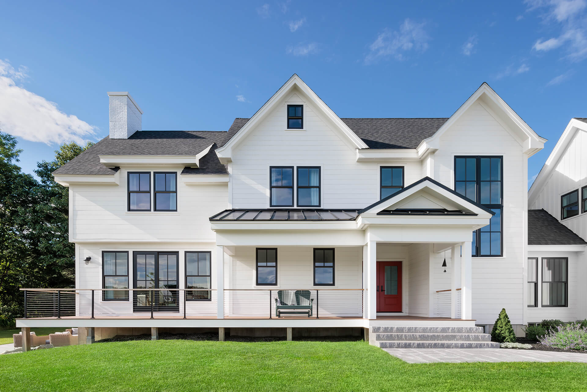 facade of white home with black windows and red door