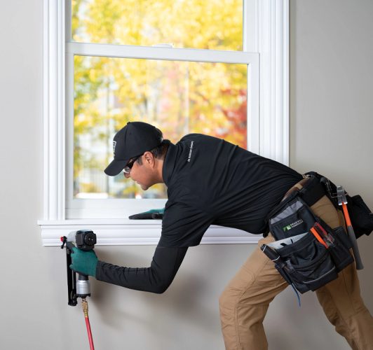 man installing white window frame